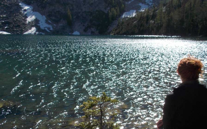 a person sits at the edge of a body of water on an outward bound course
